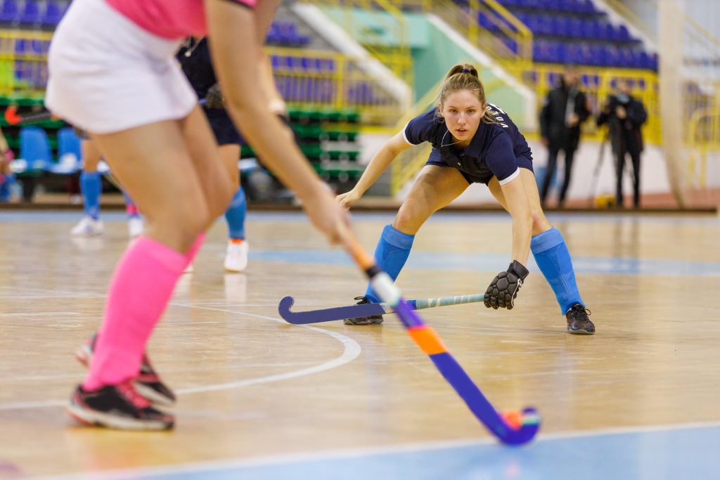 Young hockey player girl in defence against attack in indoor hockey game