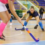 Young hockey player girl in defence against attack in indoor hockey game